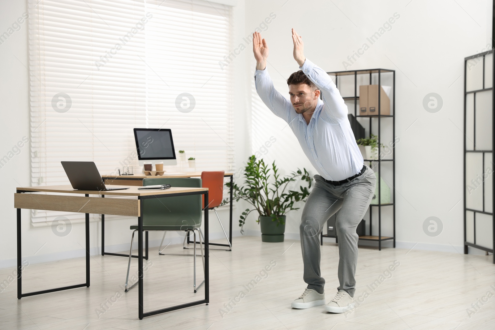 Handsome man doing exercise near desk in office Photo of Handsome man doing exercise near desk in office