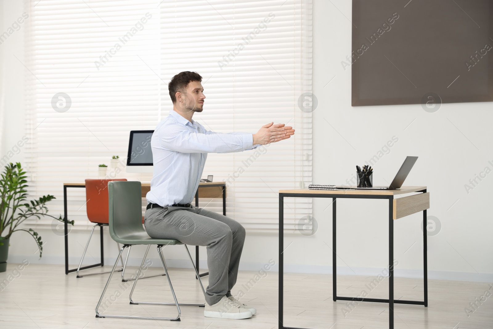 Handsome man stretching on chair in office Photo of Handsome man stretching on chair in office