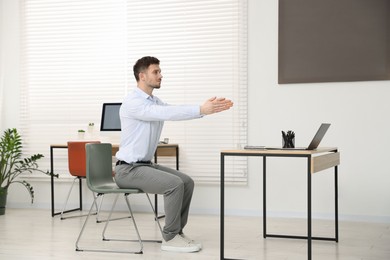 Photo of Handsome man stretching on chair in office