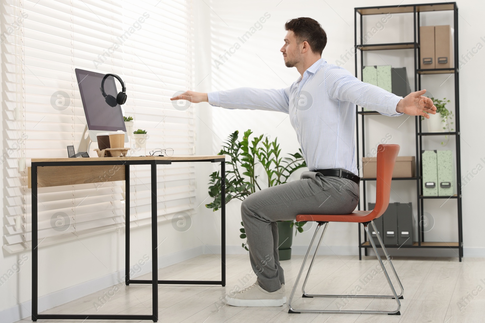 Handsome man stretching on chair in office Photo of Handsome man stretching on chair in office