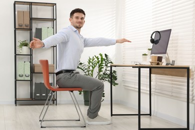 Photo of Handsome man stretching on chair in office