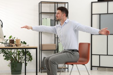 Photo of Handsome man stretching on chair in office