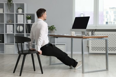 Photo of Man doing exercise with chair in office