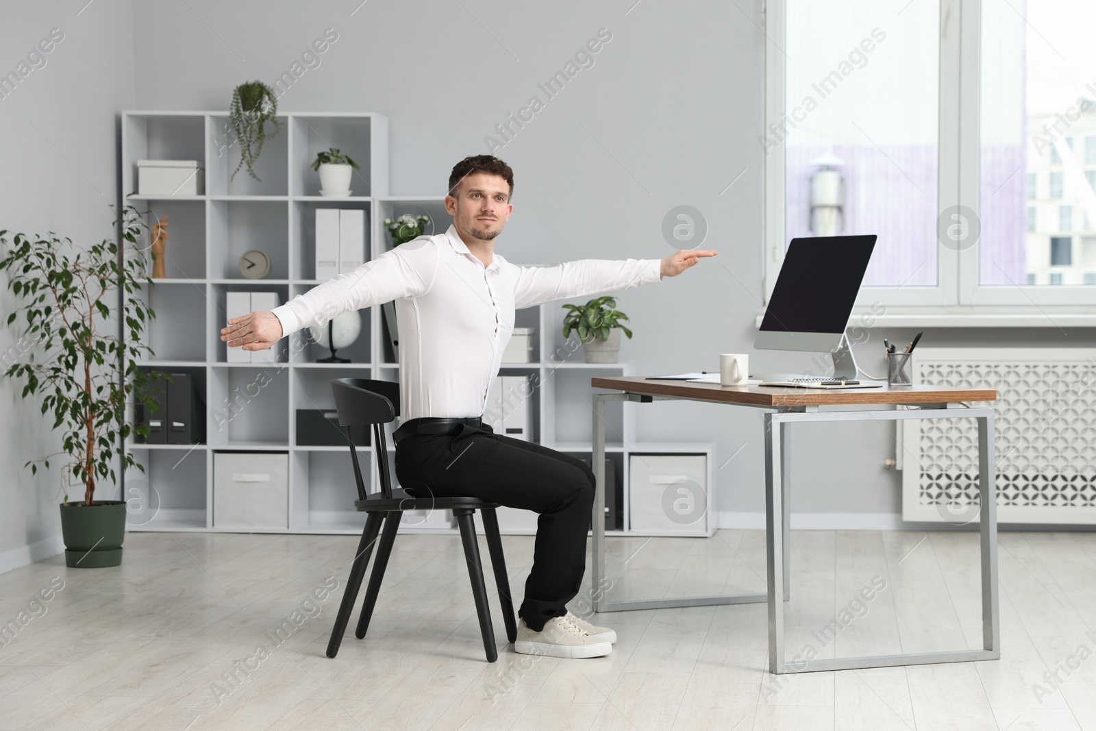 Handsome man stretching on chair in office Photo of Handsome man stretching on chair in office