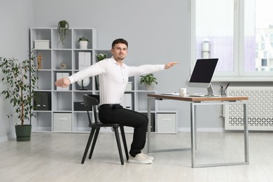 Photo of Handsome man stretching on chair in office