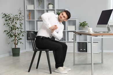 Photo of Handsome man stretching on chair in office