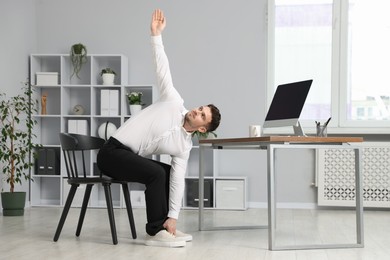 Photo of Handsome man stretching on chair in office