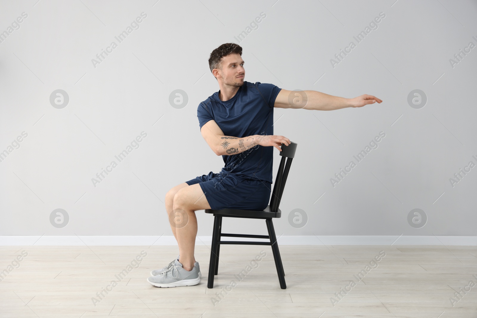 Handsome man exercising with chair at home Photo of Handsome man exercising with chair at home