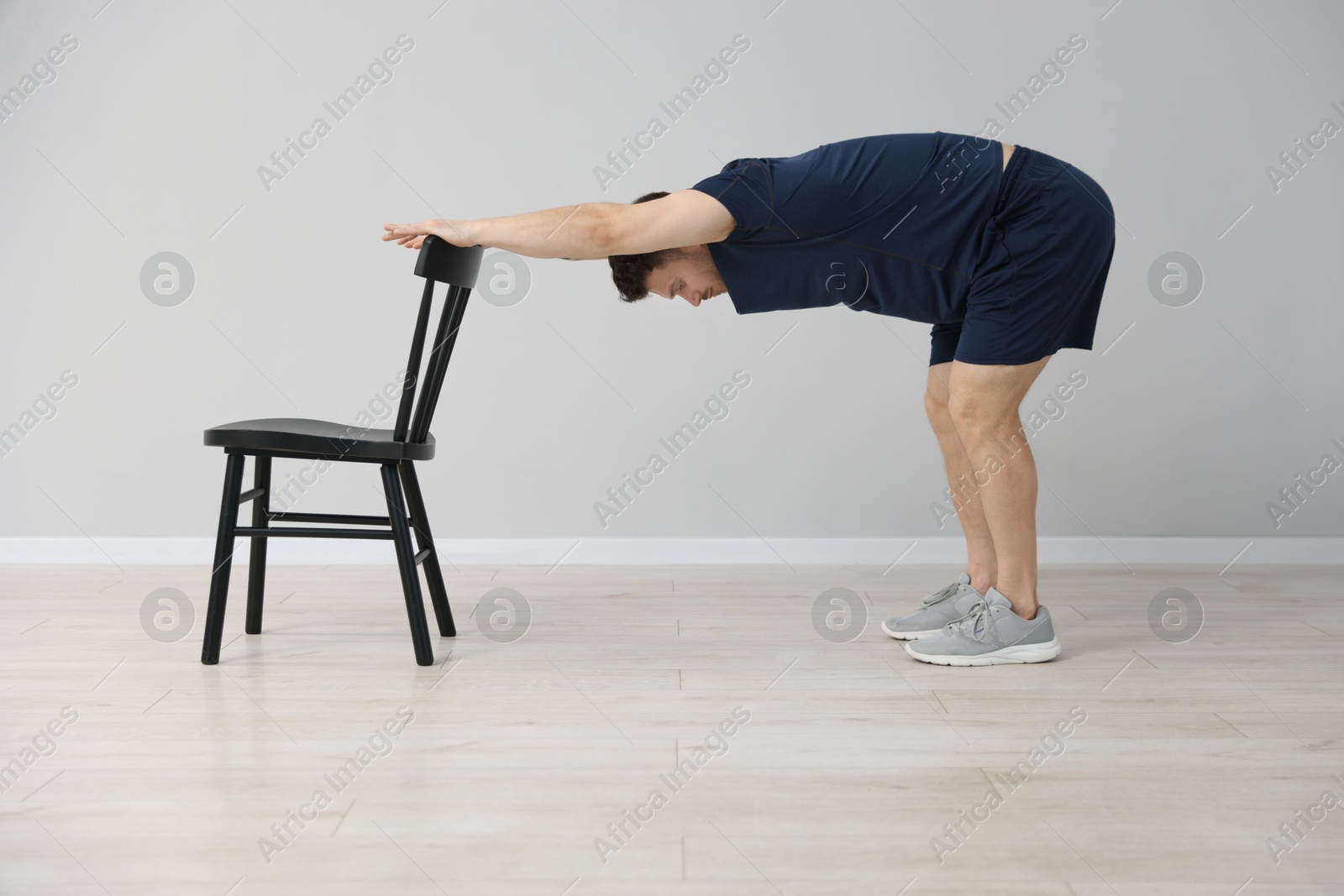 Handsome man exercising with chair at home Photo of Handsome man exercising with chair at home