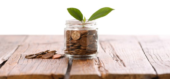 Photo of Investment concept. Glass jar with coins and sprout on wooden table against light background