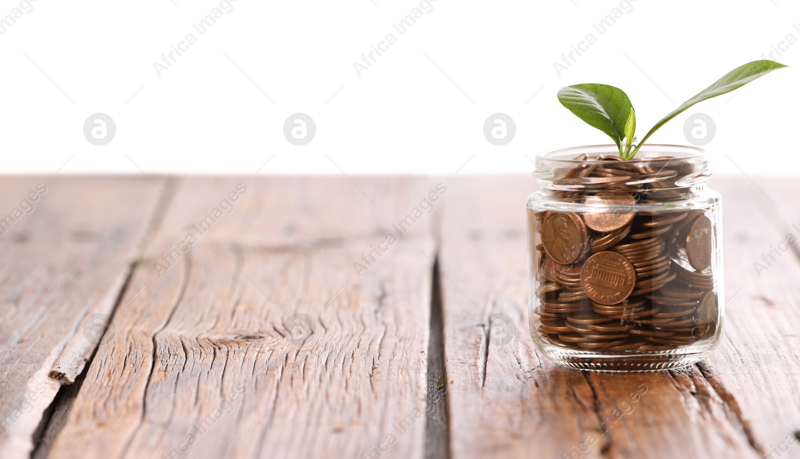Investment concept. Glass jar with coins and sprout on wooden table against light background, space for text Photo of Investment concept. Glass jar with coins and sprout on wooden table against light background, space for text