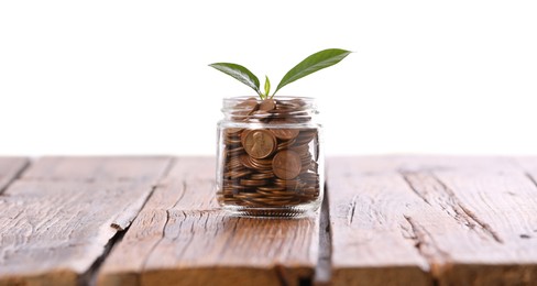 Photo of Investment concept. Glass jar with coins and sprout on wooden table against light background