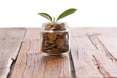 Photo of Investment concept. Glass jar with coins and sprout on wooden table against light background