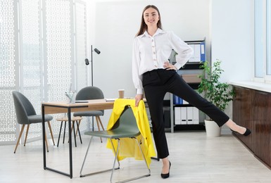 Photo of Beautiful woman exercising with chair in office