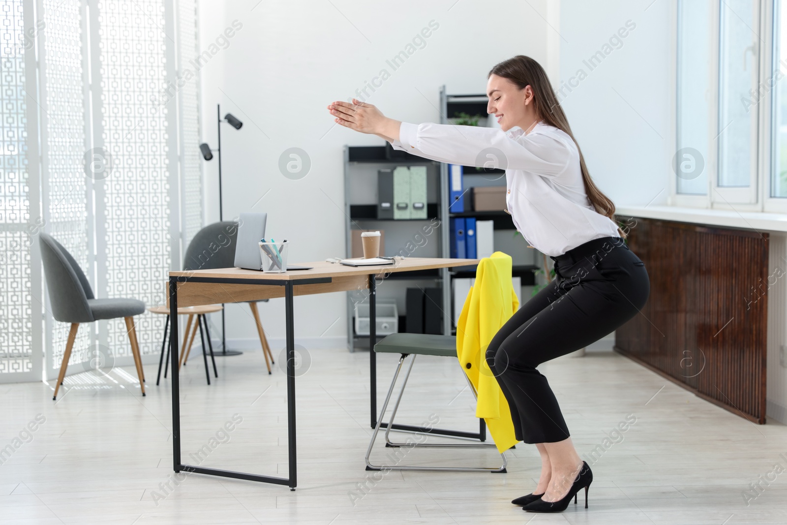 Beautiful woman doing exercise near desk in office Photo of Beautiful woman doing exercise near desk in office