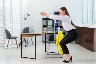 Photo of Beautiful woman doing exercise near desk in office