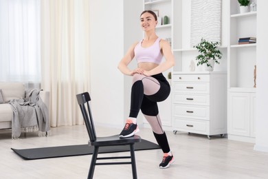Photo of Beautiful woman exercising with chair at home