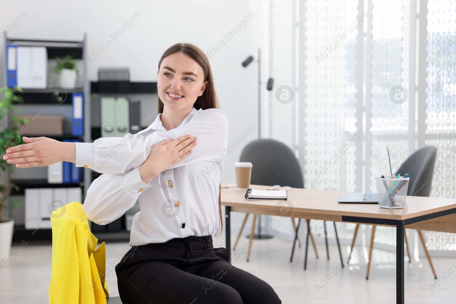 Beautiful woman stretching on chair in office Photo of Beautiful woman stretching on chair in office