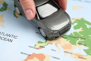 Photo of Road trip concept. Woman moving car model on world map, closeup