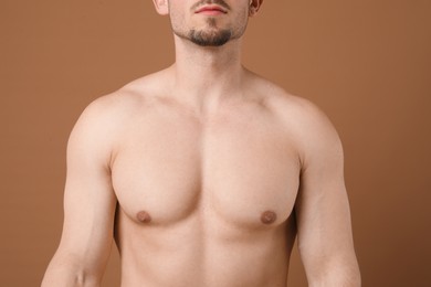Photo of Young man with smooth chest after epilation procedure on brown background, closeup