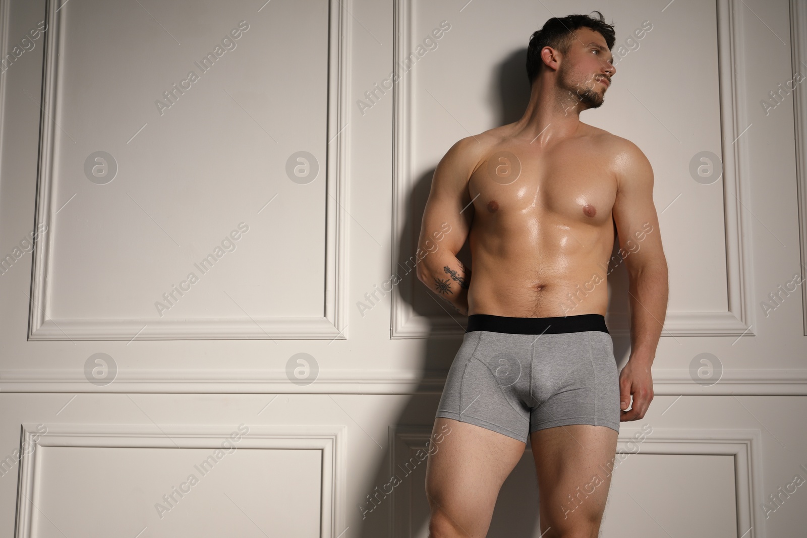 Young man in stylish light grey underwear near white wall indoors. Space for text Photo of Young man in stylish light grey underwear near white wall indoors. Space for text