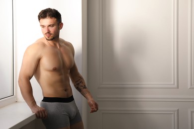 Photo of Young man in stylish light grey underwear near white wall indoors. Space for text