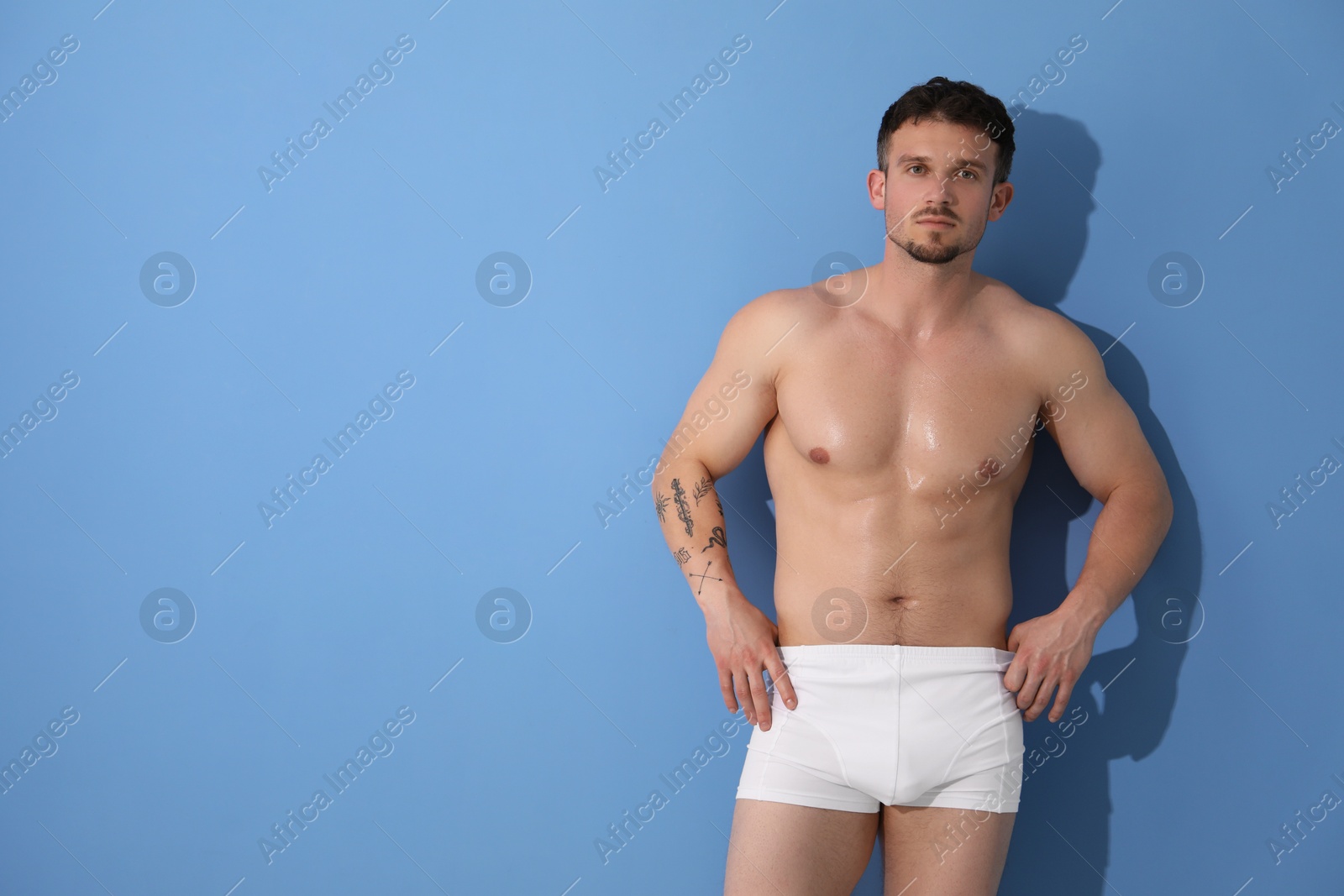 Young man in stylish white underwear on light blue background. Space for text Photo of Young man in stylish white underwear on light blue background. Space for text