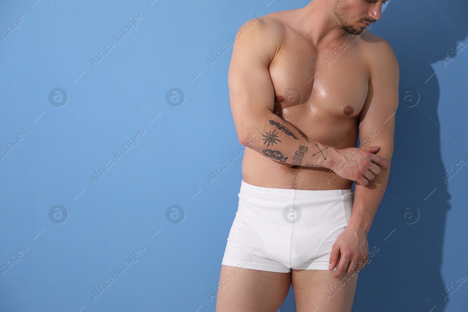 Photo of Young man in stylish white underwear on light blue background, closeup. Space for text