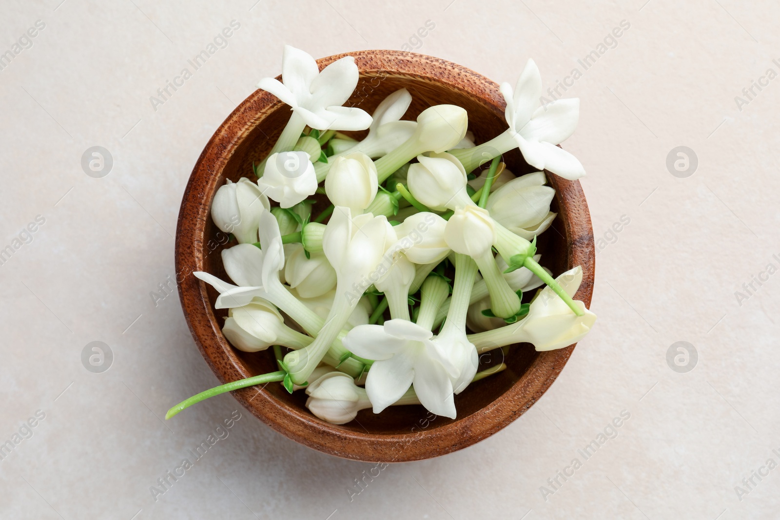 Bowl with jasmine flowers on beige table, top view Photo of Bowl with jasmine flowers on beige table, top view