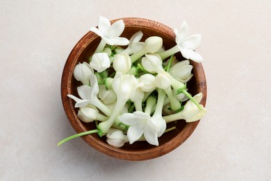 Photo of Bowl with jasmine flowers on beige table, top view