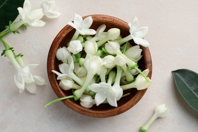 Photo of Bowl with jasmine flowers on beige table, flat lay