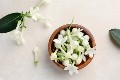 Photo of Bowl with jasmine flowers on beige table, flat lay