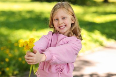 Photo of Cute little girl with beautiful dandelions in park