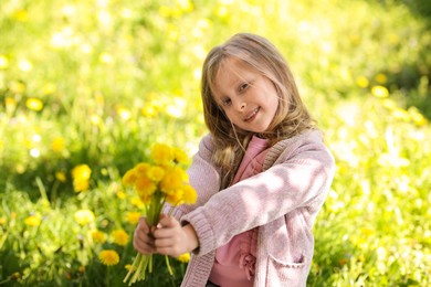 Photo of Cute little girl with beautiful dandelions outdoors on sunny day