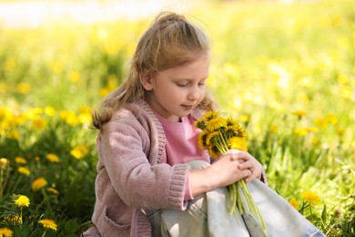 Photo of Cute little girl with beautiful dandelions outdoors on sunny day
