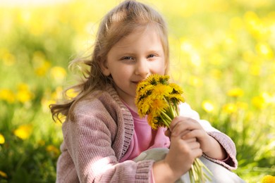 Photo of Cute little girl with beautiful dandelions outdoors on sunny day