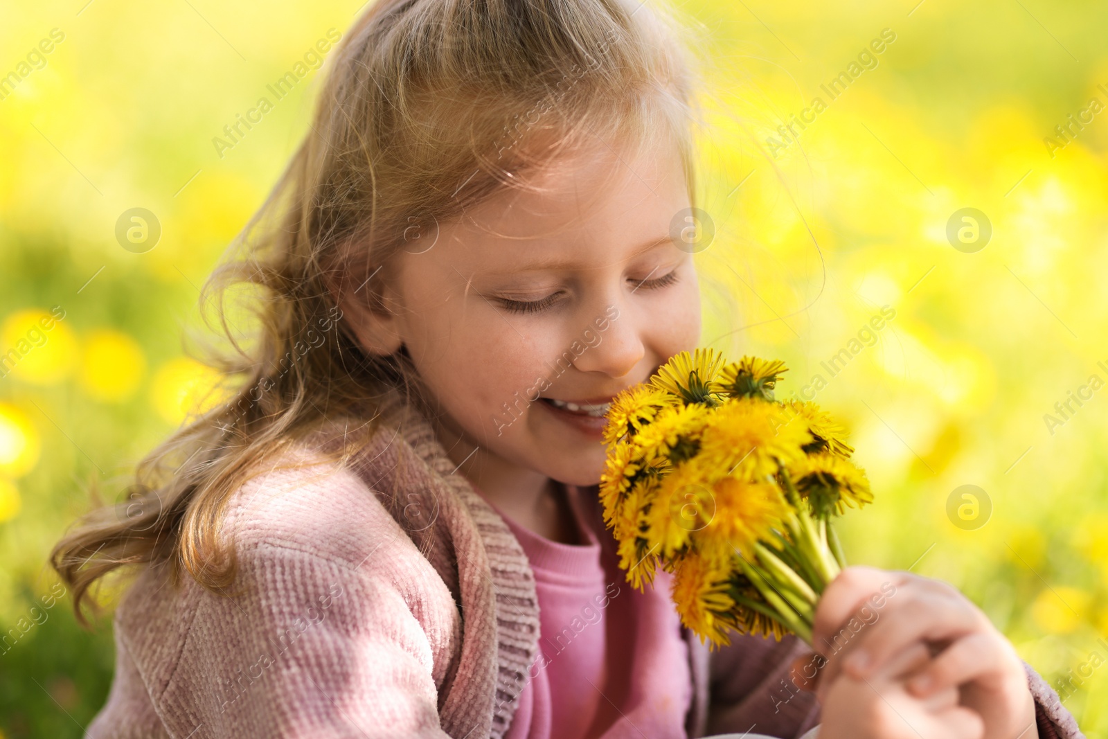 Cute little girl with beautiful dandelions outdoors on sunny day Photo of Cute little girl with beautiful dandelions outdoors on sunny day