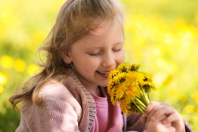Photo of Cute little girl with beautiful dandelions outdoors on sunny day