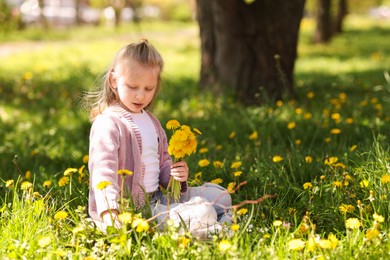 Photo of Cute little girl with beautiful dandelions outdoors on sunny day, space for text