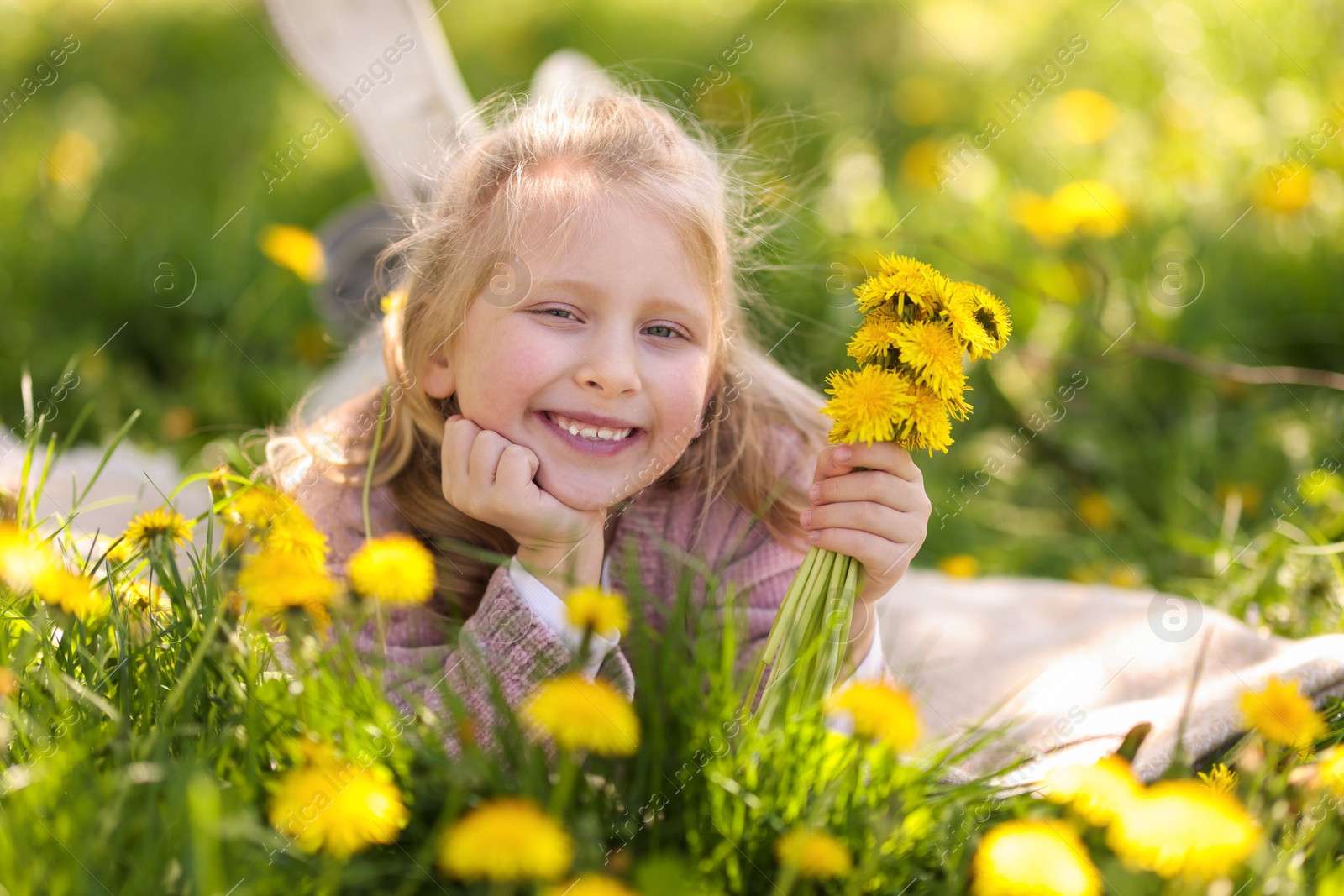 Cute little girl with beautiful dandelions on green grass outdoors Photo of Cute little girl with beautiful dandelions on green grass outdoors
