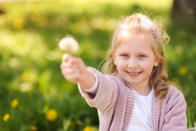 Photo of Cute little girl with beautiful dandelion outdoors, space for text