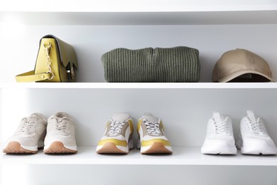 Photo of Different footwear, clothes and accessories on shelves indoors. Shoe storage