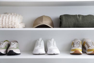 Photo of Different footwear and clothes on shelves indoors. Shoe storage