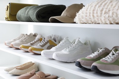 Photo of Different footwear, clothes and accessories on shelves indoors, closeup. Shoe storage