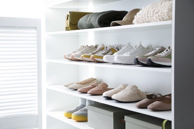 Photo of Different footwear, clothes and accessories on shelves indoors, closeup. Shoe storage