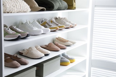 Photo of Different footwear, clothes and accessories on shelves indoors, closeup. Shoe storage