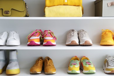 Photo of Different footwear, clothes and bag on shelves indoors. Shoe storage