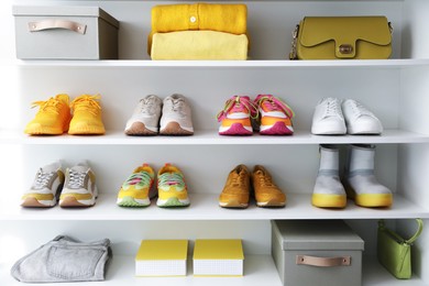 Photo of Different footwear, clothes and accessories on shelves indoors. Shoe storage