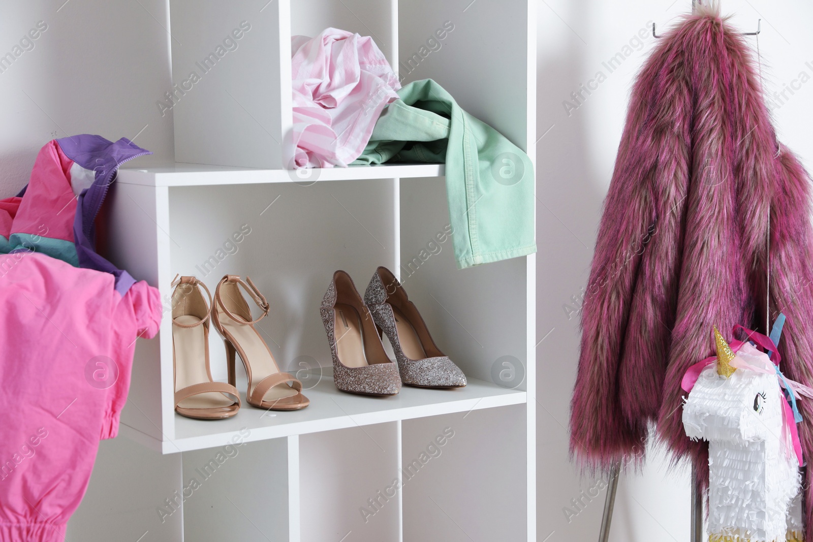 Photo of Shelving unit with different footwear and clothes indoors. Shoe storage