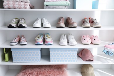 Photo of Different footwear, accessories and clothes on shelves indoors. Shoe storage